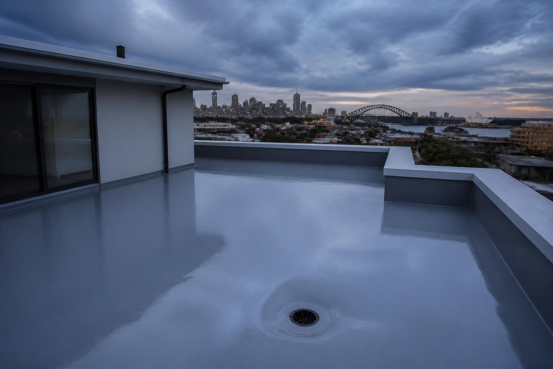 Rooftop terrace in Sydney finished with a grey waterproofing membrane, city skyline and harbour beyond